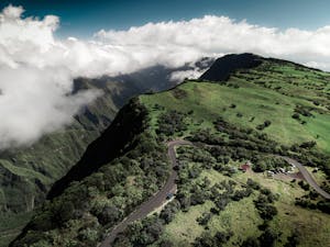 Breathtaking aerial shot of lush green highlands and winding road in Saint-Pierre, Réunion, under dramatic skies.