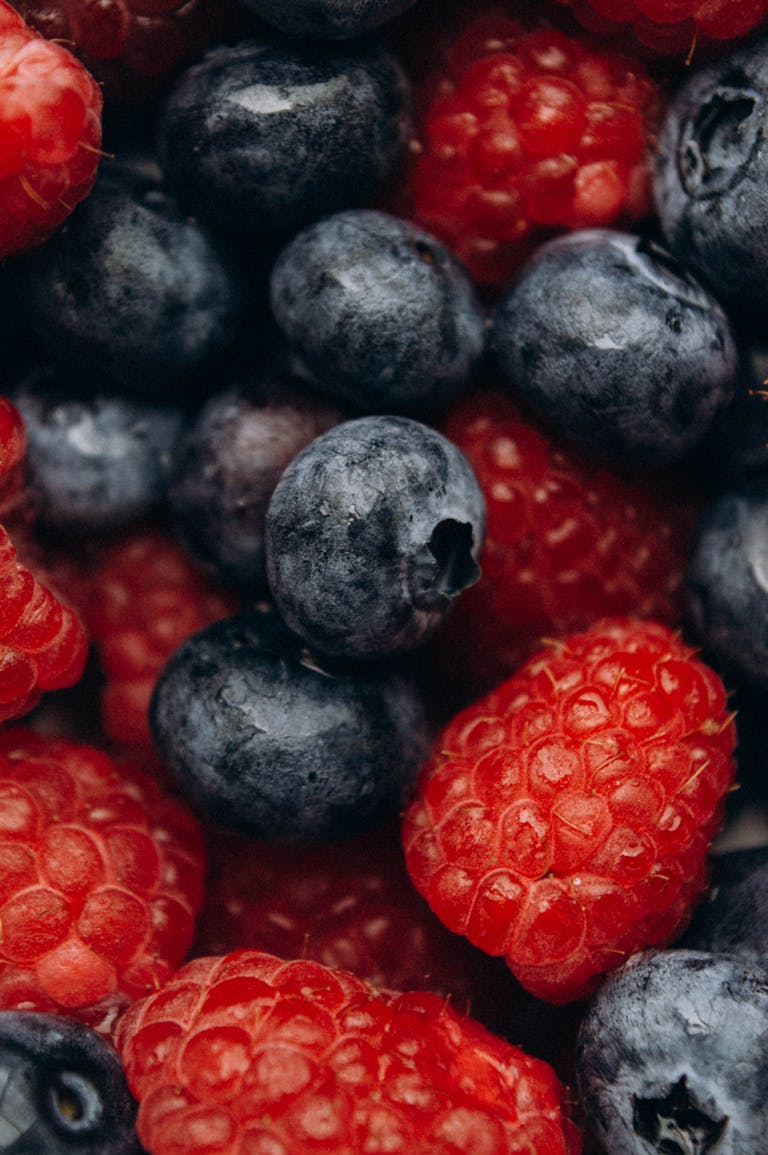 A vibrant and detailed close-up of fresh, colorful blueberries and raspberries.