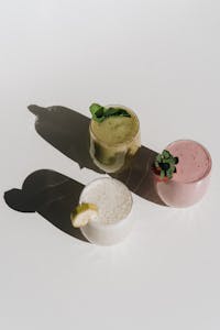 A visually appealing arrangement of three colorful fruit smoothies casting artistic shadows.