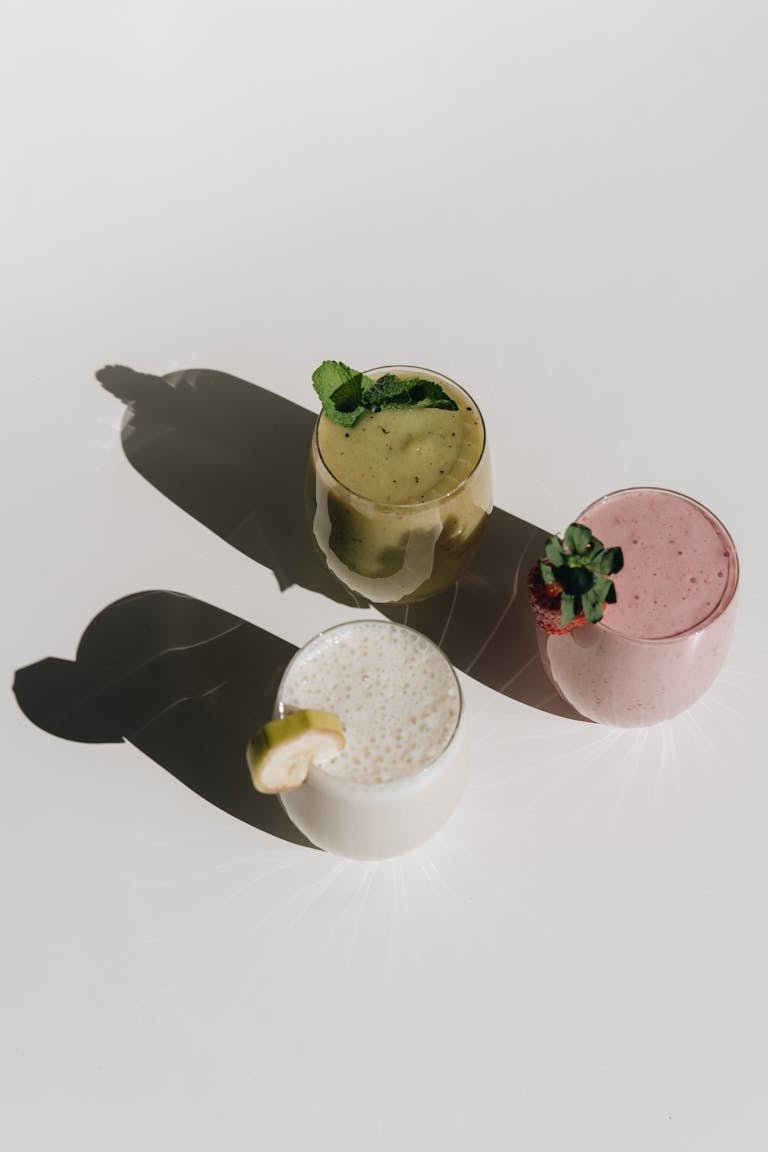 A visually appealing arrangement of three colorful fruit smoothies casting artistic shadows.