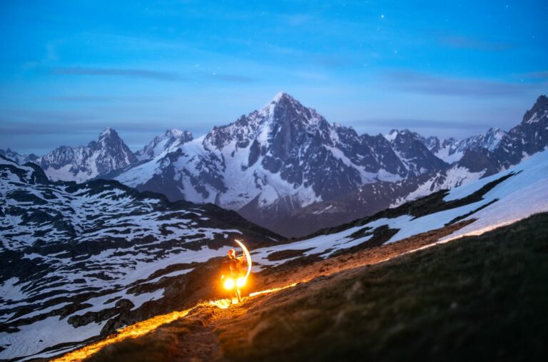 Coureur de trail sur un sentier alpin face au massif du Mont-Blanc pendant une préparation estivale.